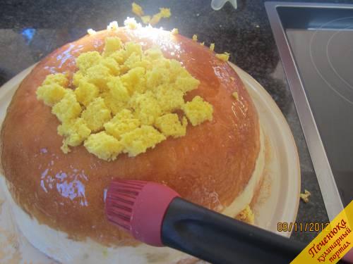 12) Перевернём торт на блюдо. Освободим от плёнки. Обильно смажем тёплым конфитюром со всех сторон. Оставшийся бисквит и лишние обрезки нарежем на мелкие квадратики. Прилепим квадратики по всей поверхности торта.