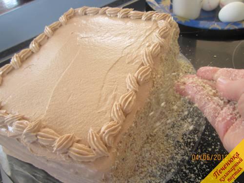 21) Обмазываем верх и бока торта шоколадным кремом. Верх торта выравниваем слегка смоченной в холодной воде лопаткой. Бока обсыпаем ореховой крошкой.