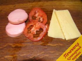 1) Острым ножом отрезать от некрупного помидора два тоненьких ломтика. Нарезать по два кусочка вареной колбасы и сыра (сыра можно взять больше, тогда бутерброд получится более нежным и сытным).