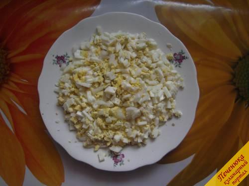 4) Следующий слой салата – яйца. Измельчаем их и выкладываем на куриное филе. На этот слой также выкладываем немного лука и смазываем его майонезом.