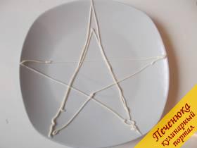 7) Приступаем к выкладке салата «Морская звезда». Чтобы нам легче было сделать форму звезды, нарисуем майонезом контуры на тарелке.