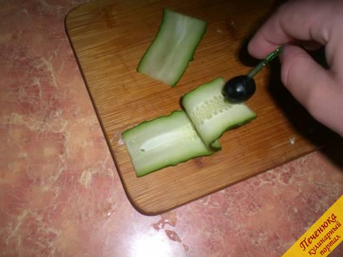 7) Огурец разрезать пополам, а после каждую половинку нарезать тонкими пластинами. На шпажку насадить маслину, порезанные пластины огурца