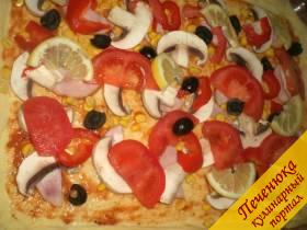 4) Сверху пиццу посыпать кукурузой консервированной, выложить помидоры, порезанные полукольцами, маслины и лимончик.