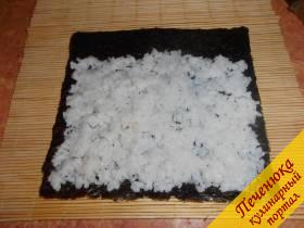 2) Заранее сварить рис, остудить его и заправить уксусом, смешанным с солью и сахаром. Выложить заправленный рис на лист нории, около 2 см листа с одной стороны не покрывать.