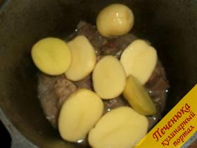 3) Почистить молодой картофель. Лучше использовать маленькие клубни. Разрезать овощ пополам и выложить поверх мяса. Немного посолить. Накрыть крышку и тушить 5-6 минуты.