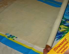 5) Раскатать тесто на доске до толщины 2 мм, затем осторожно растянуть руками на полотенце или любой ткани, слегка присыпанной мукой. Толстые края теста срезать.