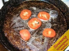 2) На раскаленную сковороду добавить кусочек сливочного масла, подождать, пока оно расплавится и выложить ломтики помидора. Помидор нужно класть раньше, чем яйца, поскольку он должен успеть немного поджариться.